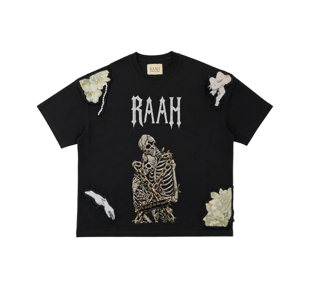A black short-sleeve t-shirt with a distressed, ripped design. The front features a large white 'RAAH' logo above a detailed skeleton graphic holding a bouquet of white flowers.