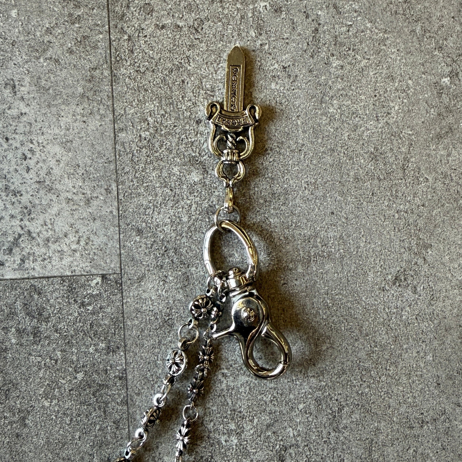 Silver chain accessory with a keychain on a gray surface