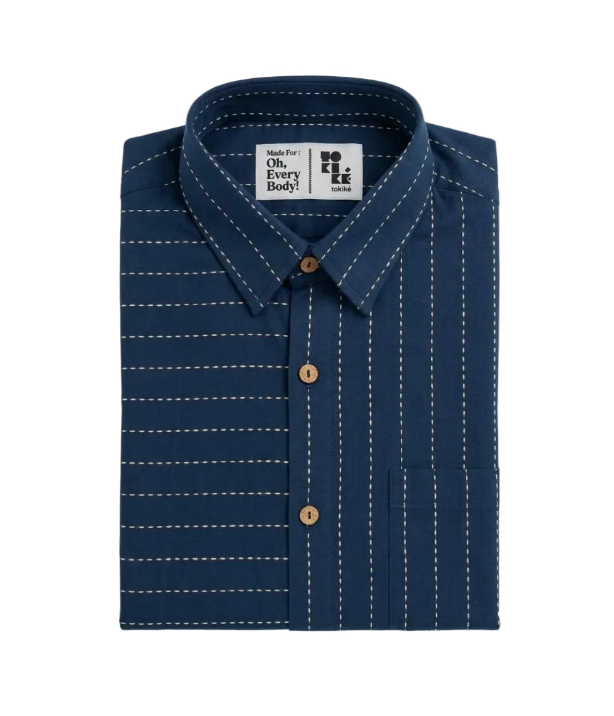 A folded navy blue button-down shirt with white pinstripes and white contrast stitching, featuring brown buttons and a visible 'Made For: Oh. Every Body.