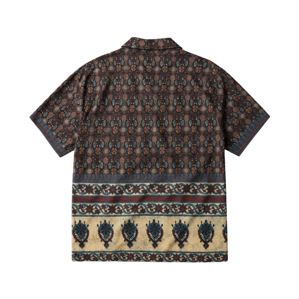 A short-sleeve button-up shirt shown flat against a white background, displaying a dark brown and black ornate pattern with a wide beige border featuring blue and brown motifs at the bottom.