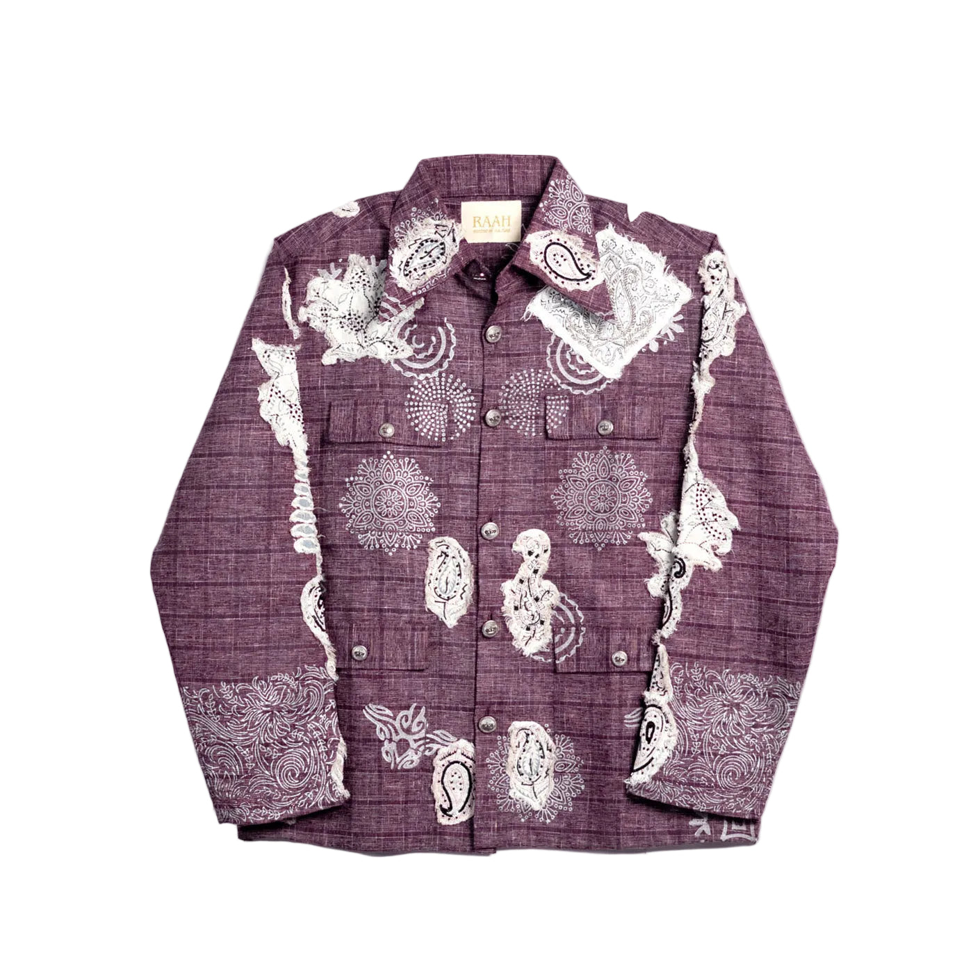 A long-sleeve button-up shirt in a deep plum purple color, featuring a subtle plaid texture and white printed illustrations of skulls, flowers, and paisley patterns, laid flat against a light off-white background.